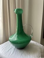 Photo of green glass retro vase or water pitcher showing side profile with clear handle and opque green body.