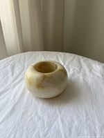 Side view of the small round beige stone tea light holder with natural color variations.