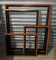 Photo showing four varying sizes of empty picture frames standing against a corrugated metal background.