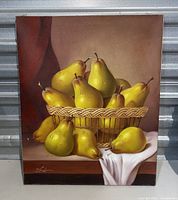 Full view of the vintage painting on canvas showing pears in a basket with some on a white cloth, signed by the artist.