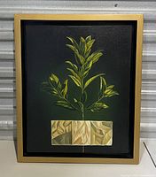 Framed painting showing green leaves and beige geometric shapes on dark background.