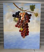 Full view of vintage canvas painting showing grape cluster with artist signature in bottom left corner and soft sky background.