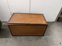 Front and top view of vintage bamboo chest. Shows woven bamboo paneling on top and sides with wooden framing.