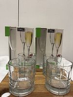 Photo showing 4 Anchor Hocking clear on-the-rocks tumblers in front of two Libbey champagne glass boxes.