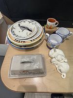 Overview photo of all ceramics including plates, creamers, butter dish, salt & pepper shakers, and Starbucks monument mug