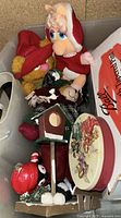 Plush Muppet Christmas dolls dressed in holiday attire along with fabric reindeer and a decorative holiday tin in a plastic bin