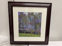 Front view of the framed print showing a landscape of eucalyptus and almond trees with a dark brown wooden frame and beige mat.