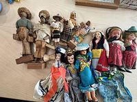 Full view of 13 dolls including folk and storybook sleepy eye dolls dressed in traditional costumes from around the world.