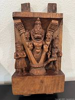 Front view of wood carving showing detailed Narasimha figure with two attendants.