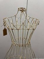 Front view of the ivory metal garden dress form showing detailed metal scroll and lattice work on the bust.