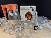 Full view of all lot items including MCM OJ carafe, boxed cocktail glasses, crystal napkin holder, chemistry bottle, and miscellaneous jars.