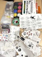 Image showing multicolor paint palette, various temporary tattoo sheets with black tribal and symbolic designs, packages of fake eyelashes, and green body jewelry.