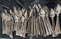 Full set of flatware displayed, showing forks, knives, tablespoons, teaspoons with tarnish and vintage condition.