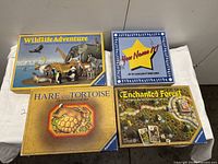 Four board games arranged side by side showing the game boxes and lids: Wildlife Adventure, You Name It, Hare and Tortoise, and Enchanted Forest.