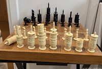Photo showing full set of white and black Barleycorn pulpit chess pieces arranged on wooden case with chessboard top.
