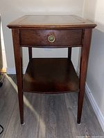 Image of wooden end table with one drawer and lower shelf, showing missing knob on the drawer's screw cover.