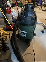 Shop Vac 10 gallon wet/dry vacuum in a basement or workshop setting, showing the body, hose, and motor section.