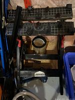 Photo showing the black Jobmate work table with measurement markings, clamps, and blue vise grip attached.