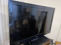 Black Sanyo flat screen television with 50 inch display placed against wall on stand.