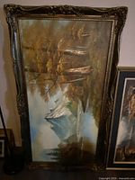 Full view of large landscape painting with ornate dark carved frame showcasing nature scene with water and trees.