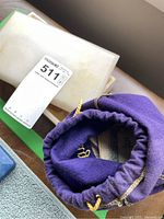 Purple cloth drawstring bag partially open showing paper money and some coins inside.