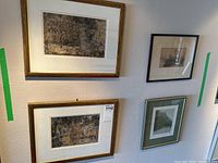 Four framed prints on a wall: two large gold‐framed abstracts at left, one smaller black frame at top right, one wood frame with green mat at bottom right.
