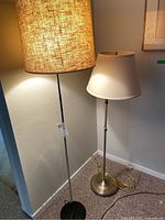 Two metal base floor lamps placed side by side, showing relative height and shades.