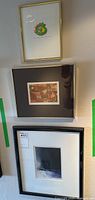 Three framed prints displayed on wall (one small gold frame, two larger black frames)