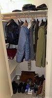 Closet with hanging jackets and shoes below, hats and scarves on shelf above