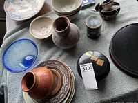 Overhead view showing cloisonne jar, lacquer server lid, pottery bowls, decorative platter, pottery vase, two artisan bowls and hand-blown glass bowl.