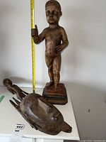 Overview of wood Christ child statue and Bamana Ntomo mask on table with ruler.