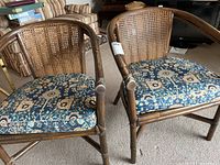 Two rattan chairs side by side showing full front view, cushions and armrests visible