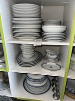 Shelves of stacked white dishware with blue decorative patterns including plates and bowls