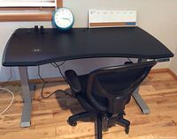 Desk with curved black top, silver legs and chair in front