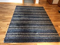 Full view of blue rectangular area rug with horizontal stripe pattern on hardwood floor.