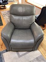 Front view of grey leather recliner showing seat cushion, backrest and armrests.