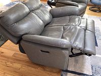 Side view with footrest extended showing grey leather upholstery and power recline lever