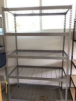 Front view of heavy duty metal shelving with four wire grid shelves and perforated steel frame.