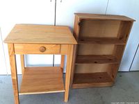 Two wooden furniture pieces including a side table with drawer and a small bookshelf side by side.