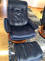 Front view of navy blue leather recliner and matching ottoman on area rug