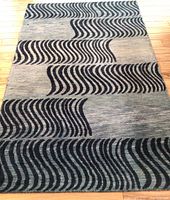 Full view of the rectangular West Elm 5x8 rug showing the wave pattern in dark blue on a lighter blue and gray background, laid on a wood floor.