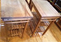 Front view of two wooden rolling kitchen islands showing butcher block tops and slatted shelves