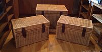 Three wicker baskets arranged side by side on wood floor, lids closed