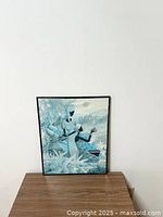 Framed African art print showing two women and peacocks in nature with some wear visible on the print and frame.