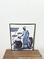 Full view of the framed African print showing the woman, pots, and background with trees.