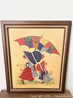 Close-up of framed picture showing two Holly Hobby girls with umbrella, patchwork and floral dresses, with signs of wear on picture and frame.