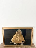 Full frontal view of the gold foil sailing ship picture in wooden frame showing detailed sails and the black background.