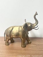 Side profile of the brass elephant figurine showing the raised trunk and prominent ears.