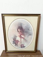 Framed Victorian-style portrait of a young woman, oval mat with flowers, gold-toned wooden frame with minor wear.