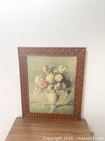 Front view of the framed vintage floral print on a table against a plain wall.
